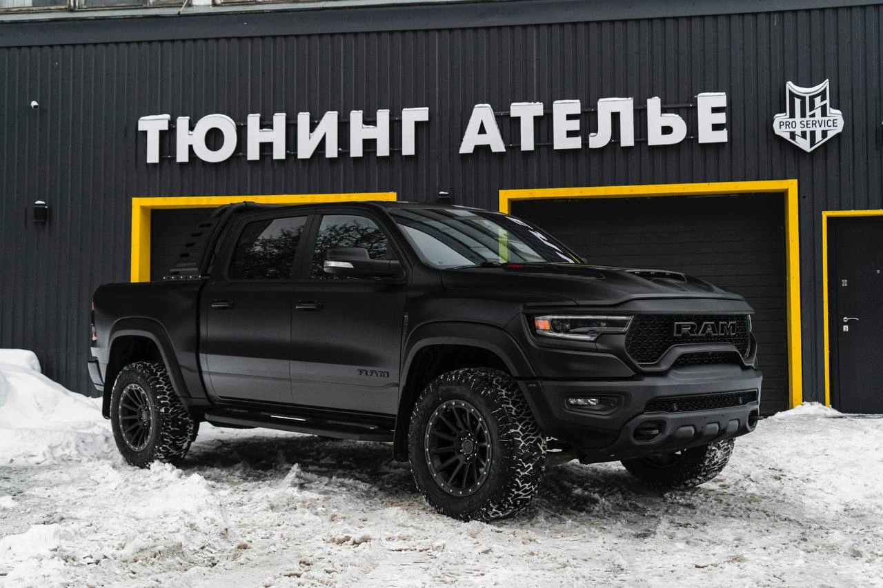 Dodge Ram TRX — тёмный пикап спереди под углом на заснеженной площадке у ателье