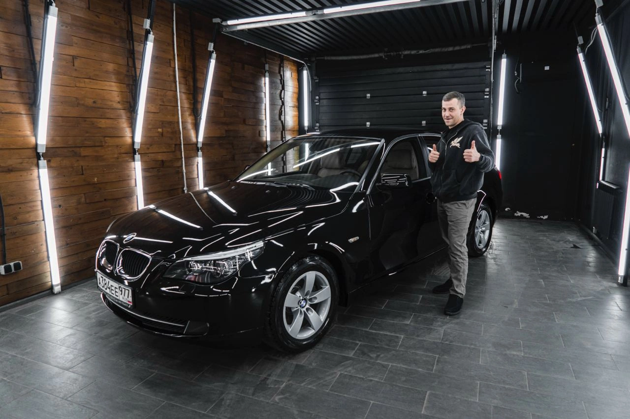 BMW 5 E60 — чёрный седан в рабочем боксе, рядом стоит человек
