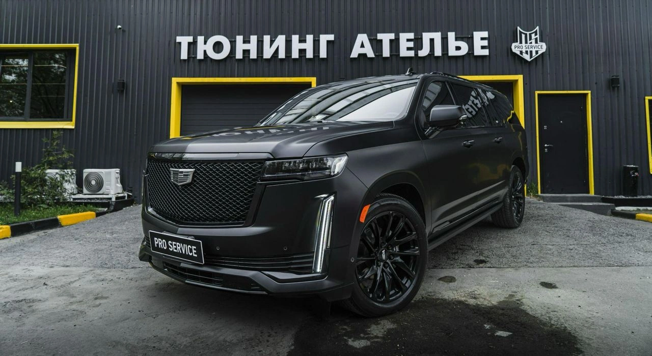 Cadillac Escalade ESV diesel у ворот ателье: серый кузов, тёмные колёса и вертикальные передние огни.