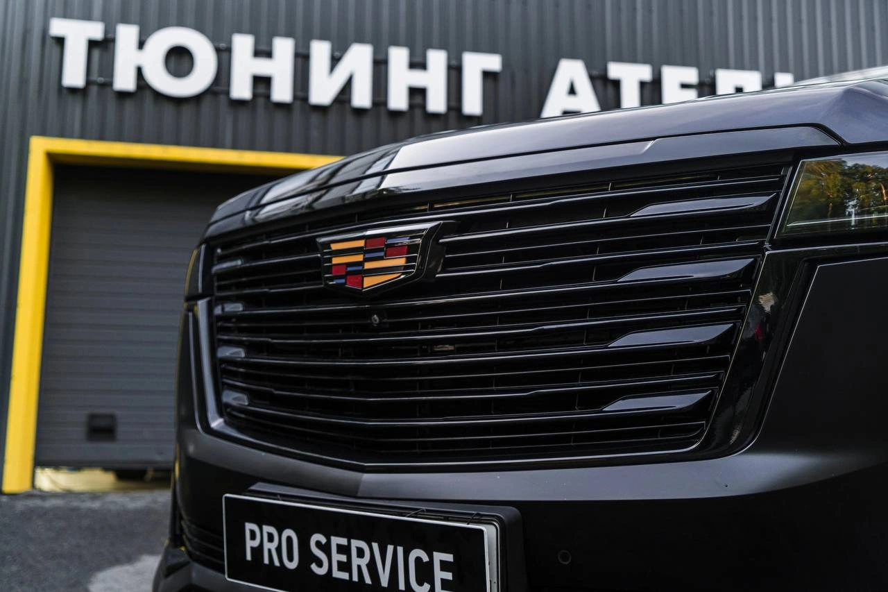 Cadillac Escalade — крупный план чёрной решётки и эмблемы на передней части кузова