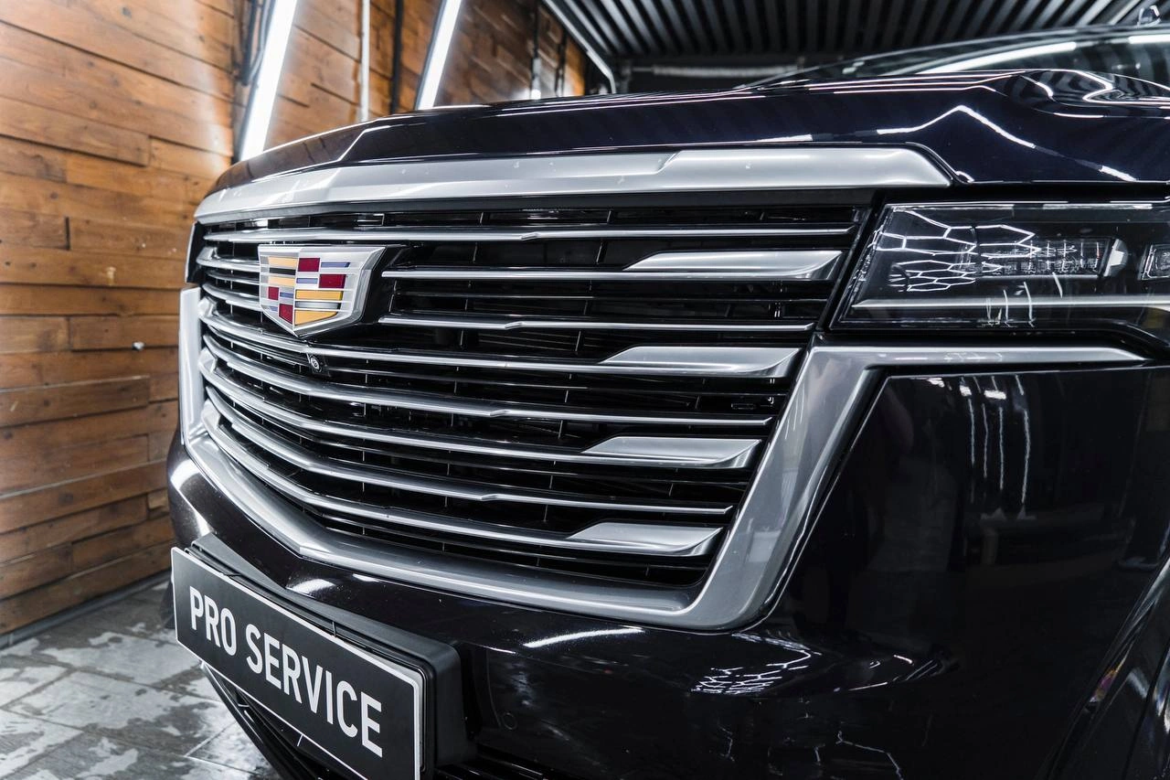 Cadillac Escalade — хромированная решётка радиатора, эмблема и передняя фара крупным планом