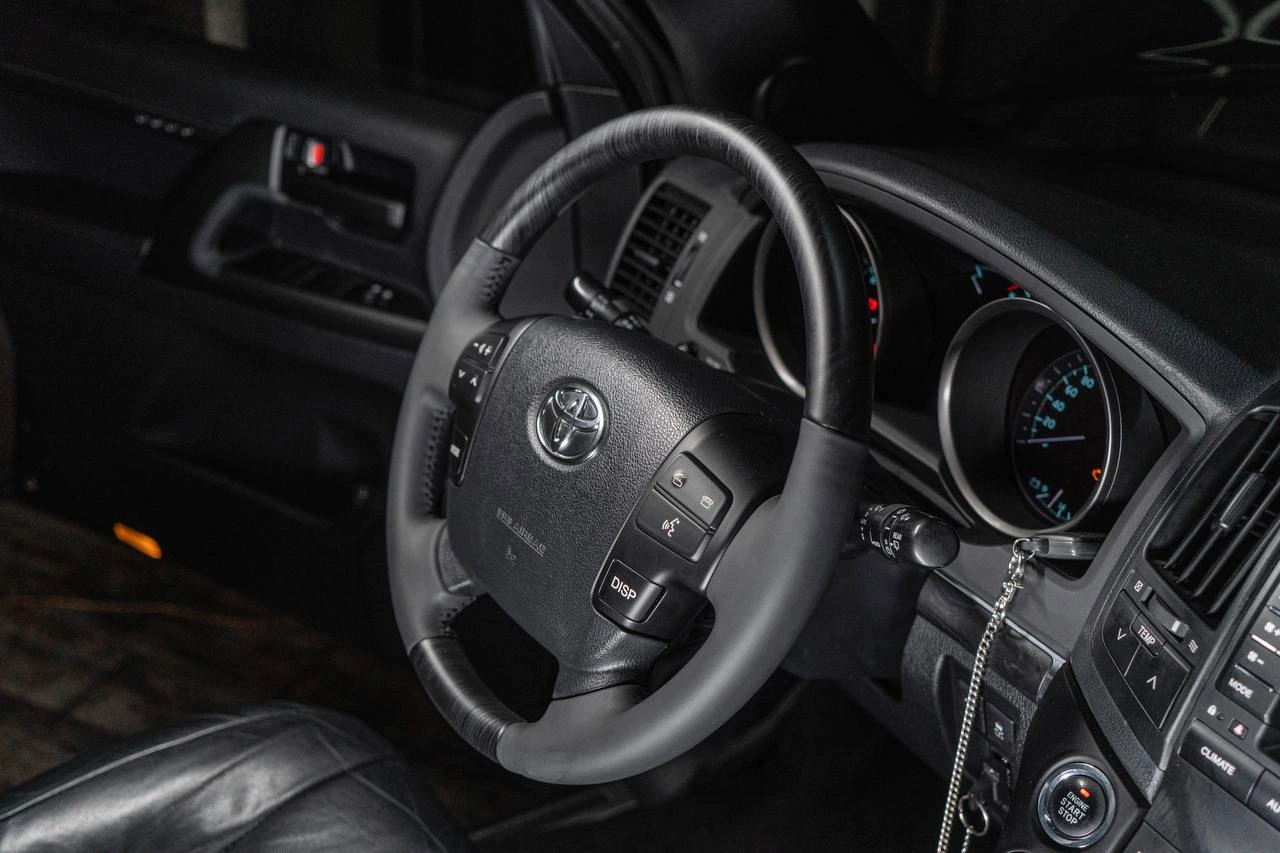 Toyota Land Cruiser 200 — рулевое колесо, приборная панель и часть центральной консоли в тёмном салоне