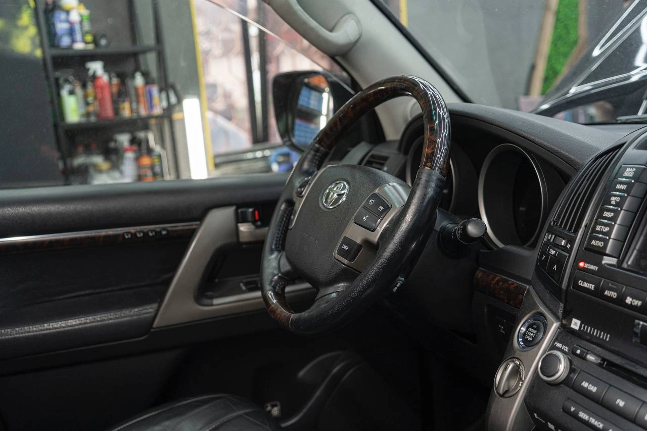 Руль Toyota Land Cruiser 200 с кожаной отделкой и вставками под чёрное дерево.