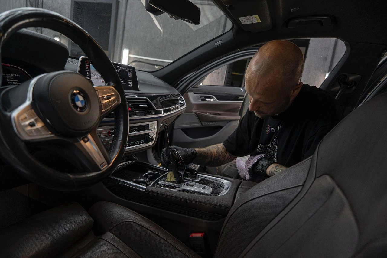 Мастер очищает центральную консоль BMW 7-й серии рядом с селектором передач.