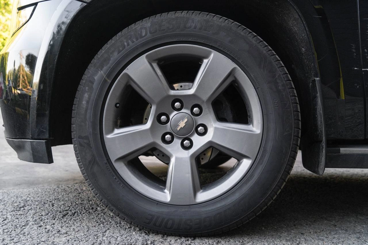 Светлый пятиспицевый диск Chevrolet Tahoe сбоку крупным планом, видны крепёжные отверстия и боковина шины.