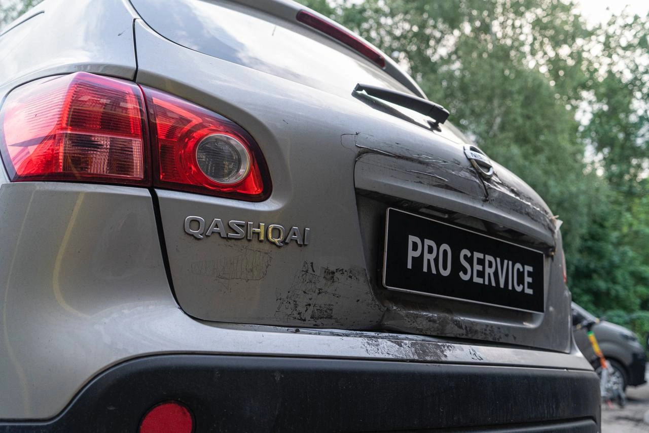 Повреждения лакокрасочного покрытия на крышке багажника Nissan Qashqai крупным планом.