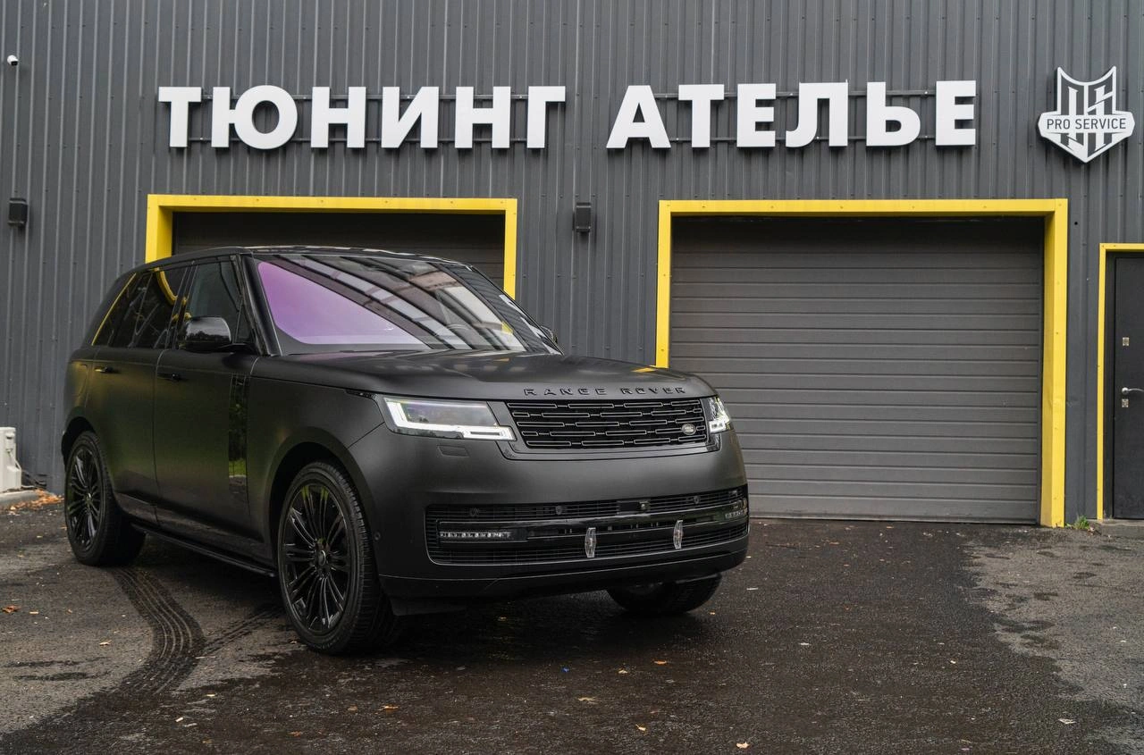 Тёмный Range Rover с матовой фактурой кузова, вид спереди под углом у входа в студию.