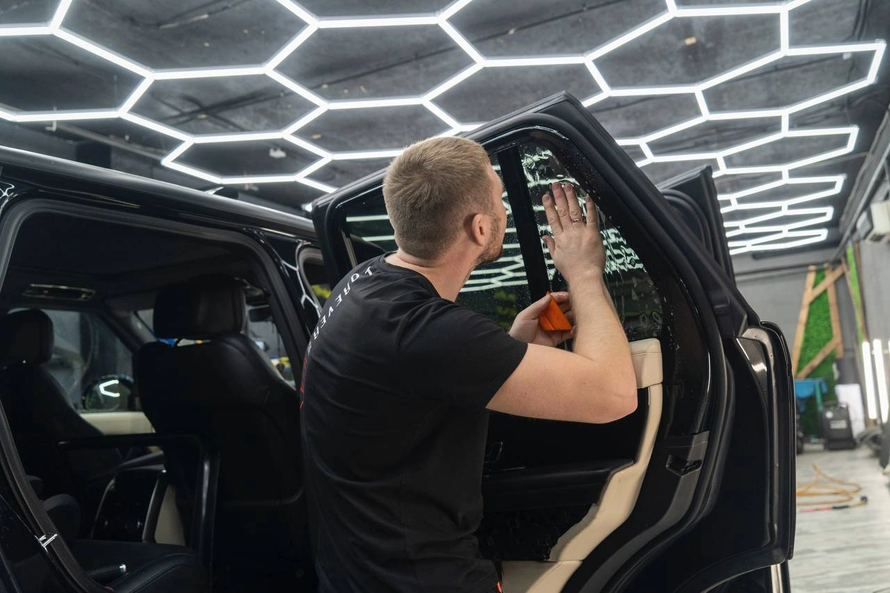Мастер работает с внутренней отделкой Range Rover у открытой задней двери автомобиля.