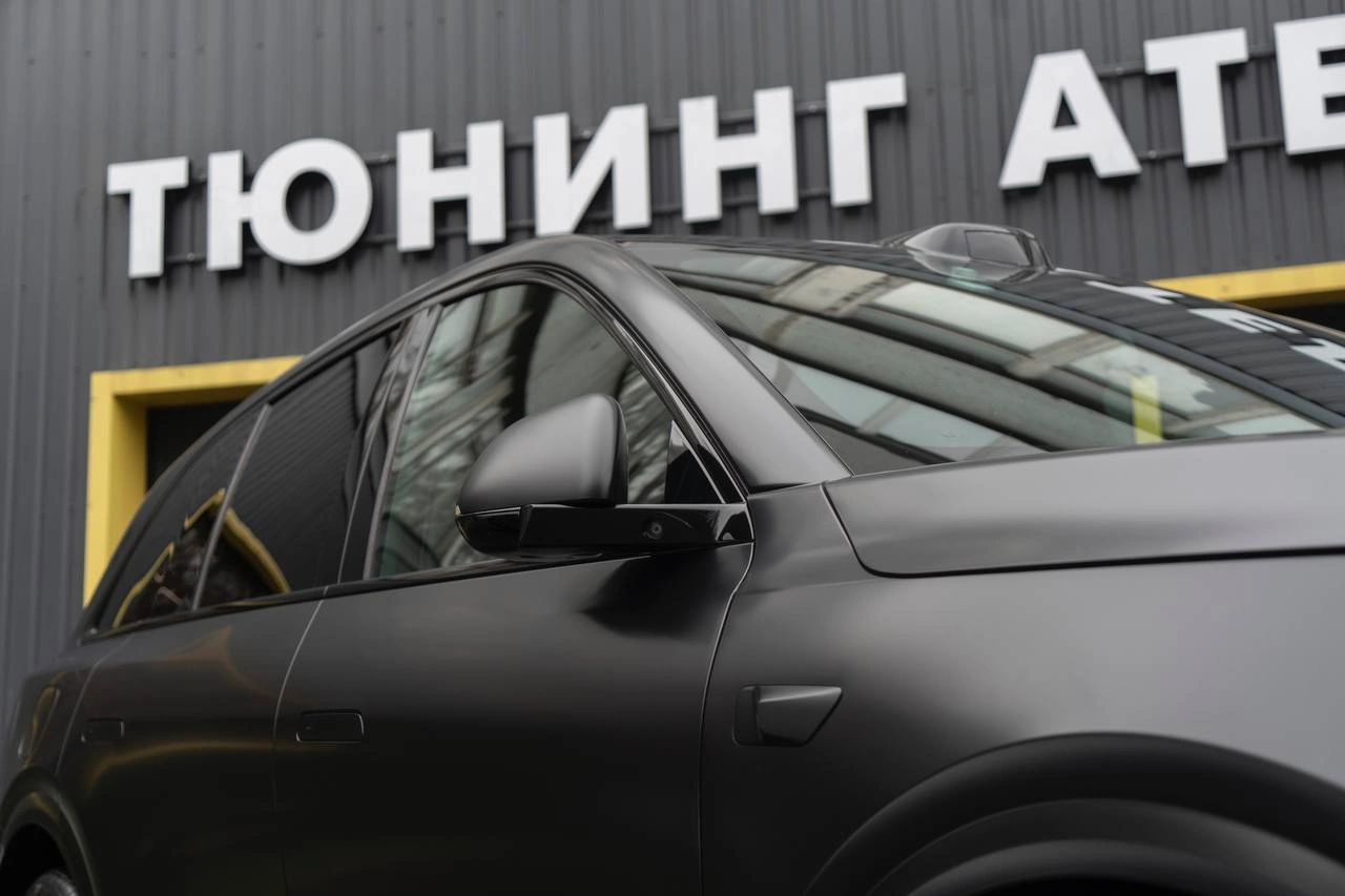 Боковая часть серого Lixiang L6 крупным планом: матовая дверь, зеркало и тёмная окантовка окон.