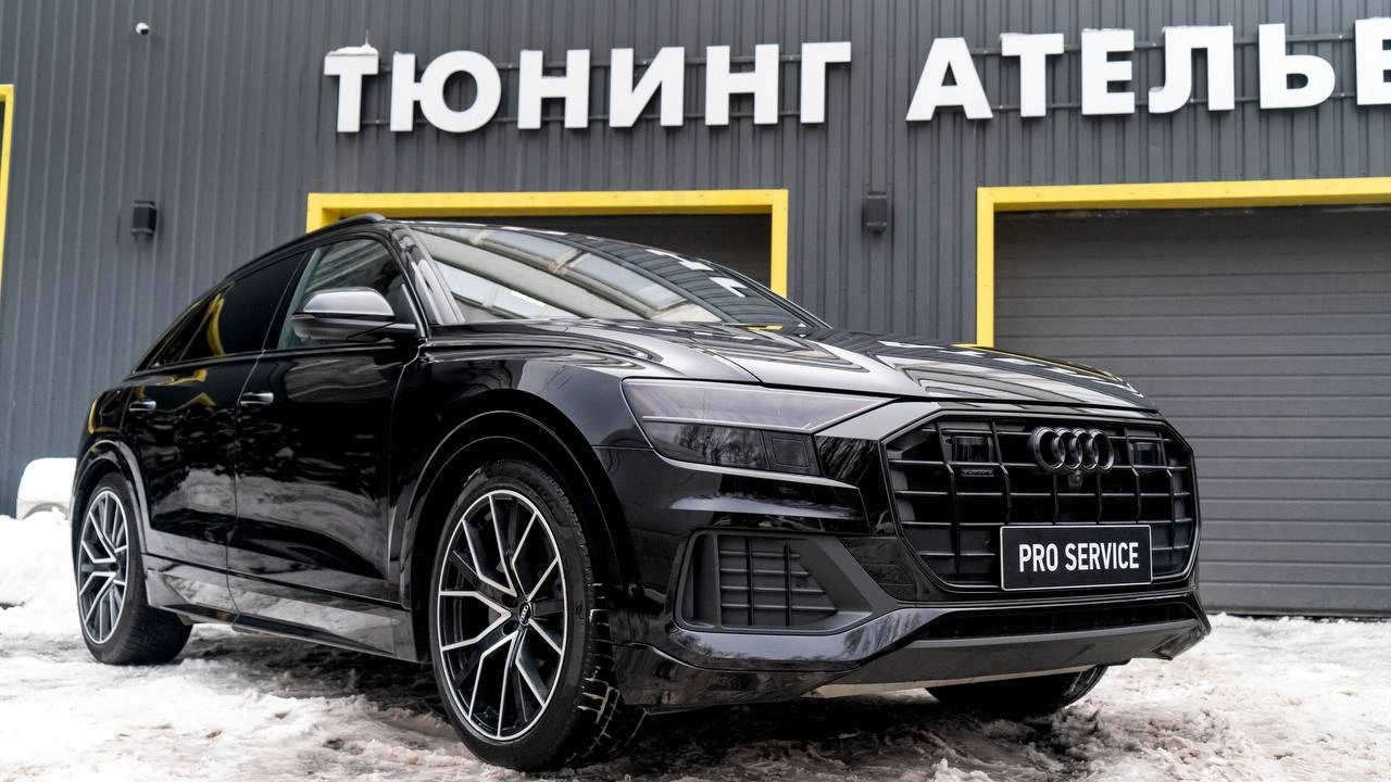 Audi Q8 — чёрный кроссовер спереди под углом на площадке перед тюнинг-ателье
