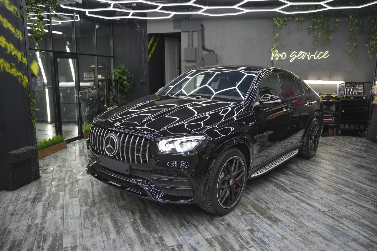 Mercedes-benz GLE — чёрный внедорожник спереди под углом с отражениями световых линий на кузове