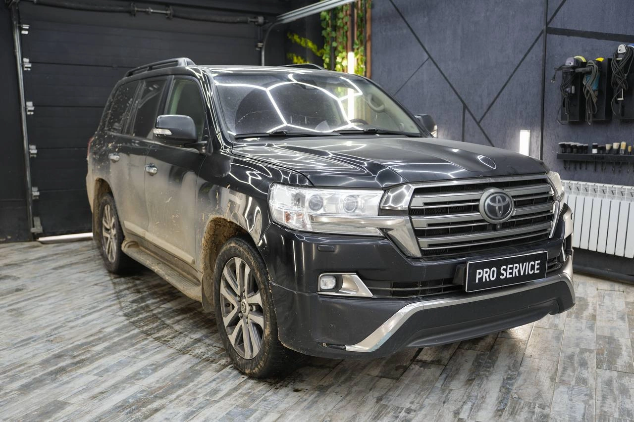 Toyota Land Cruiser 200 с загрязнениями на нижней части кузова, вид спереди под углом.