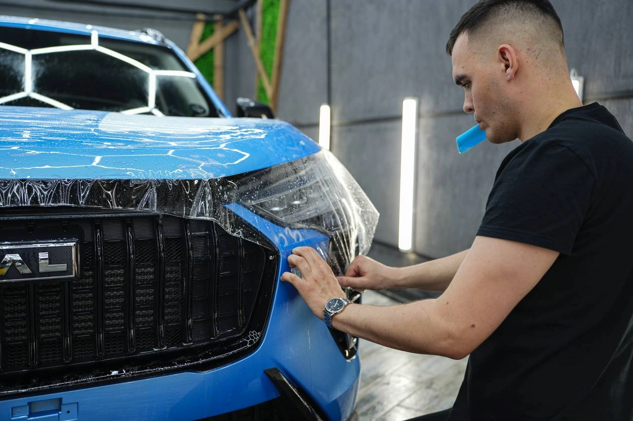 Подгонка защитной плёнки на переднем бампере голубого Haval Jolion.