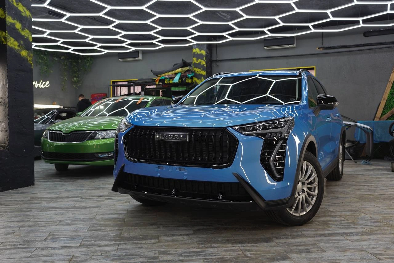 Голубой Haval Jolion в боксе после оклейки зон риска защитной плёнкой.