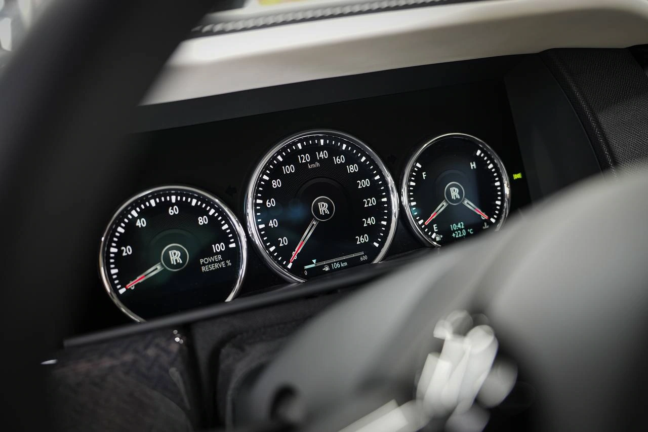 Приборная панель Rolls-Royce Cullinan крупным планом: три круглые шкалы и монограммы в центральной части.
