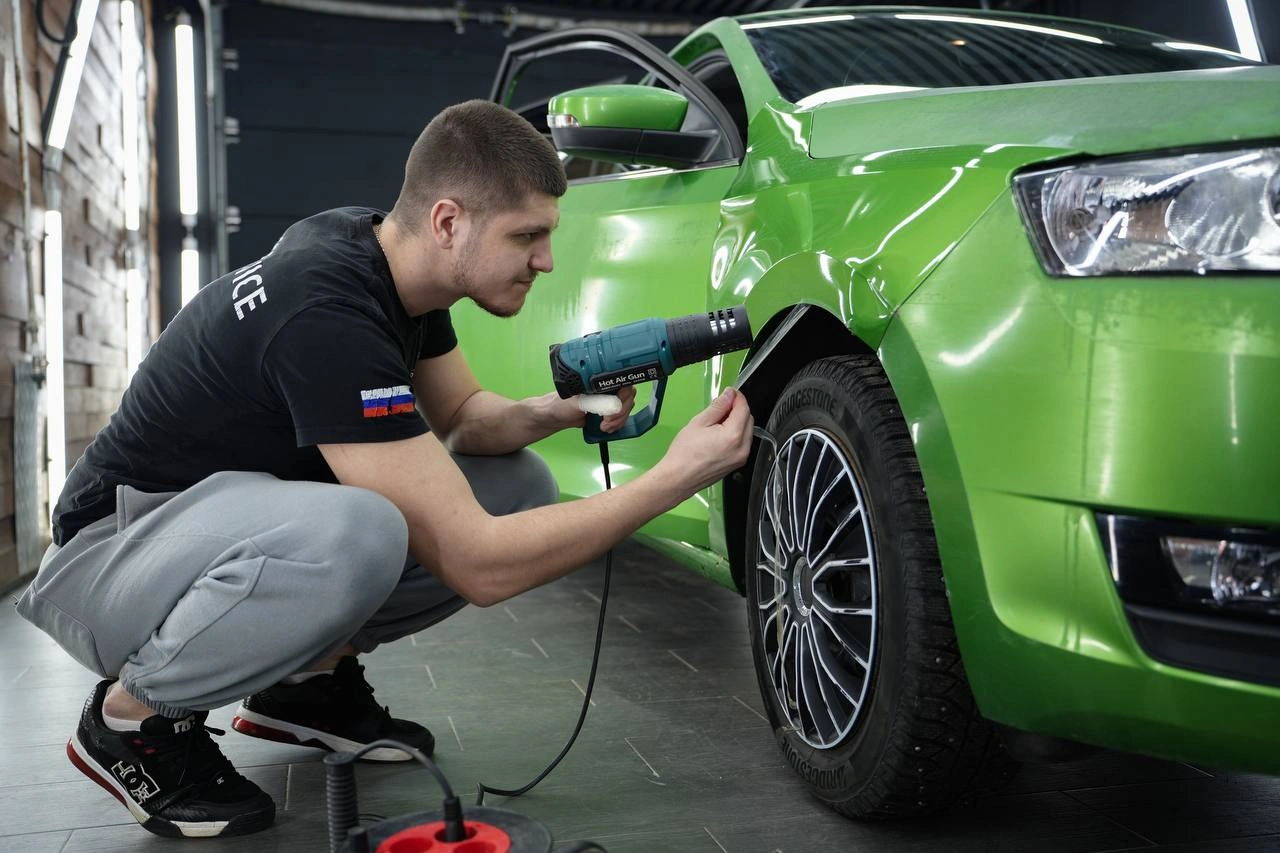 Skoda Rapid — мастер прогревает плёнку феном у передней колёсной арки