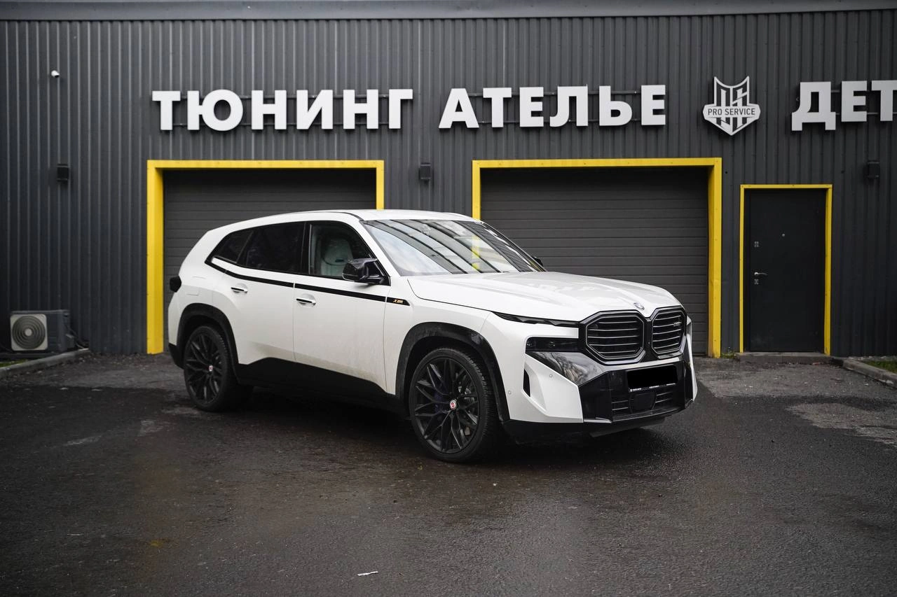 Белый BMW XM перед изменением цвета кузова, вид спереди сбоку у ателье.
