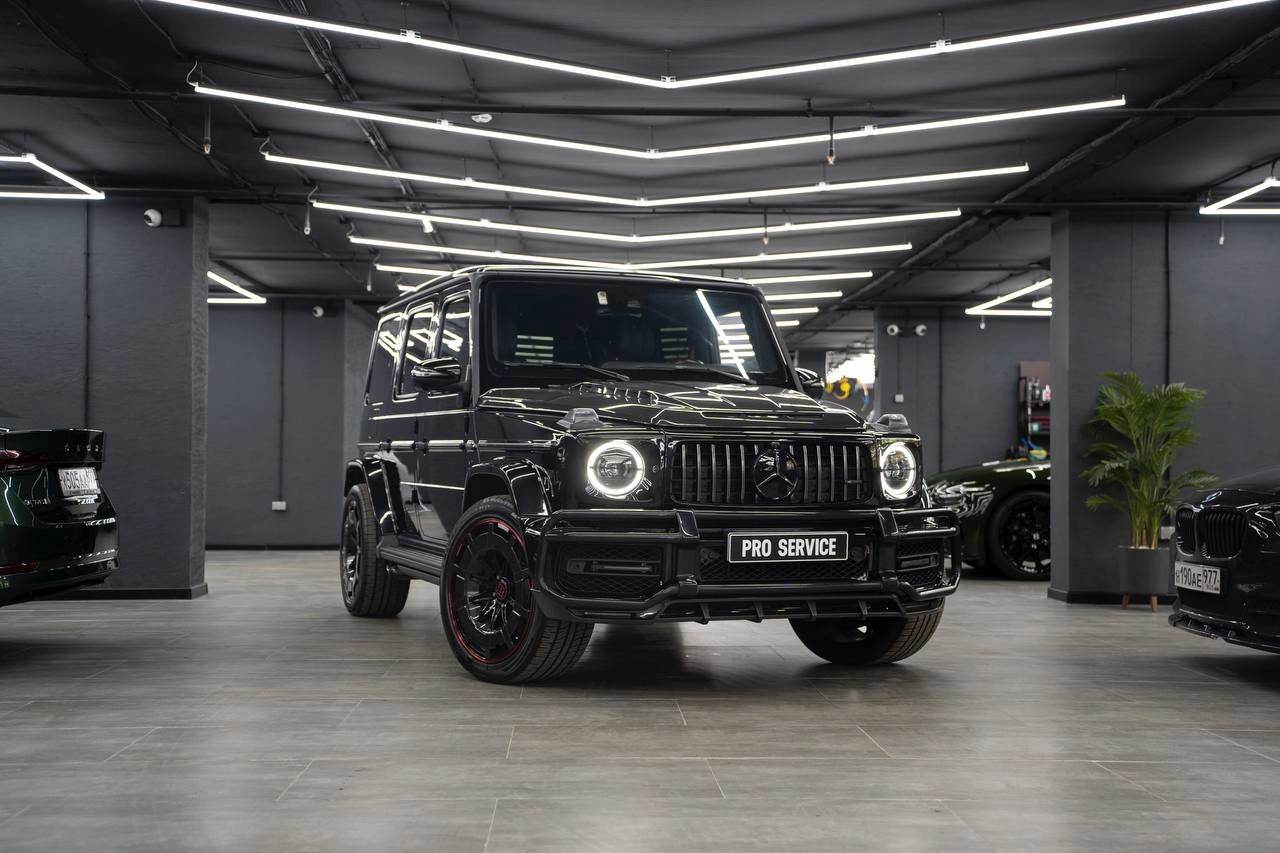 Чёрный Mercedes-Benz G-class AMG в студии: вид спереди и сбоку, круглая оптика и широкие колёсные арки.