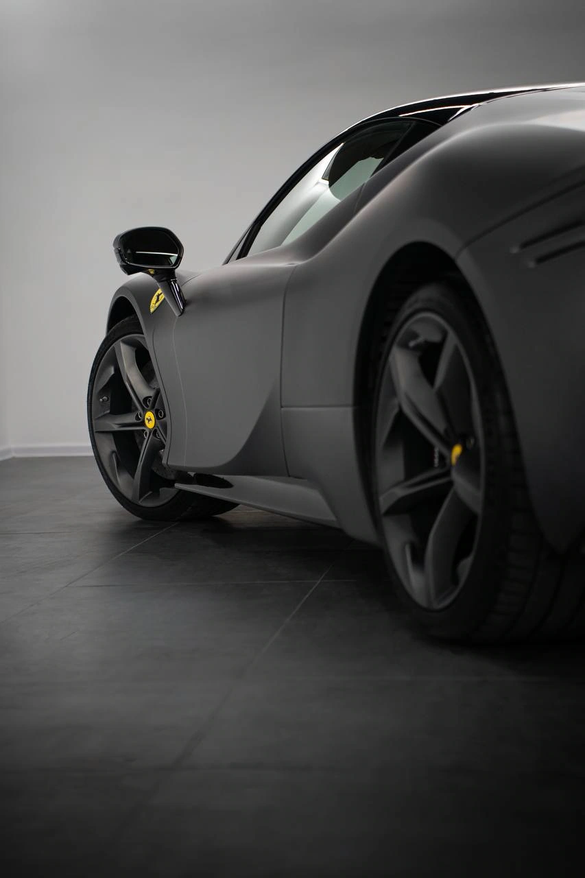 Ferrari SF90 Stradale — боковая линия серого кузова и колёса спорткара с низкого ракурса