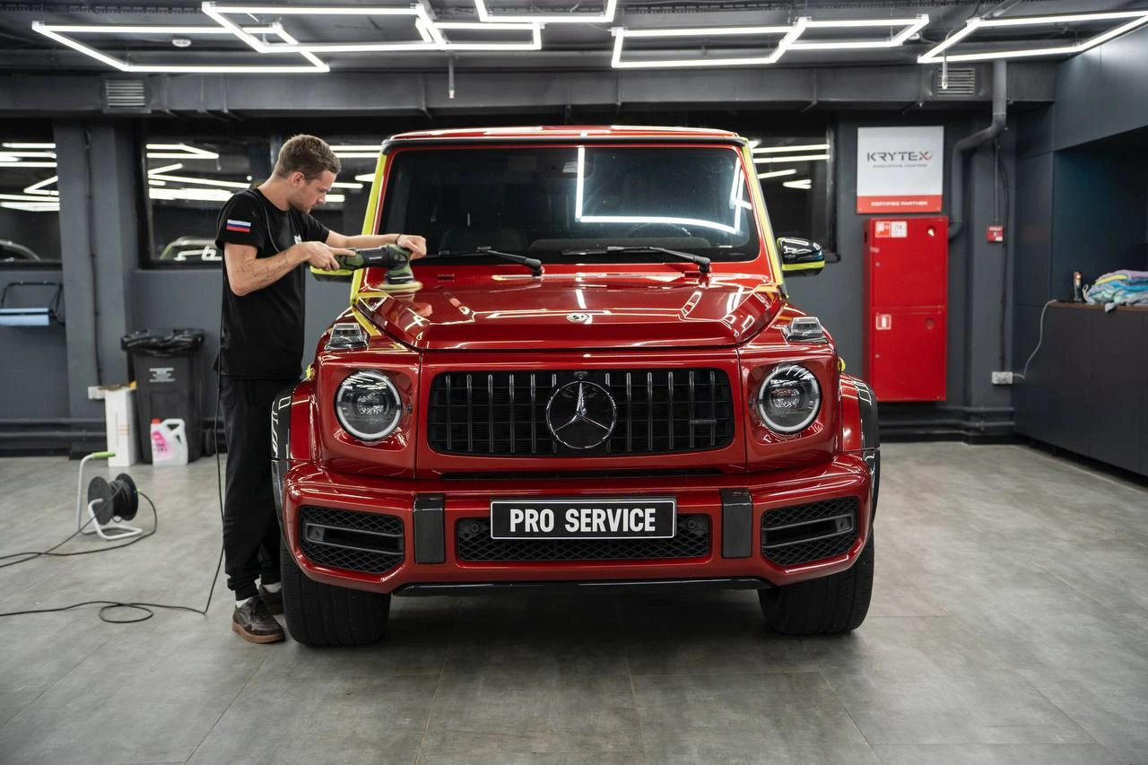 Мастер протирает капот Mercedes-Benz G-Class во время детейлинга кузова.