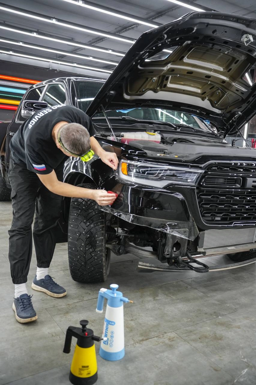 Подгонка защитной плёнки у передней фары Dodge Ram при открытом капоте.