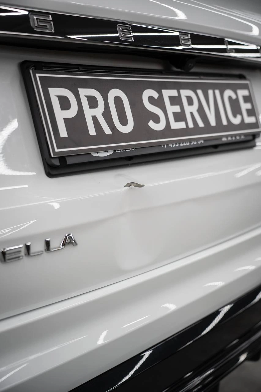 Задняя часть белой Geely Tugella крупным планом: номерная рамка, крышка багажника и бампер.