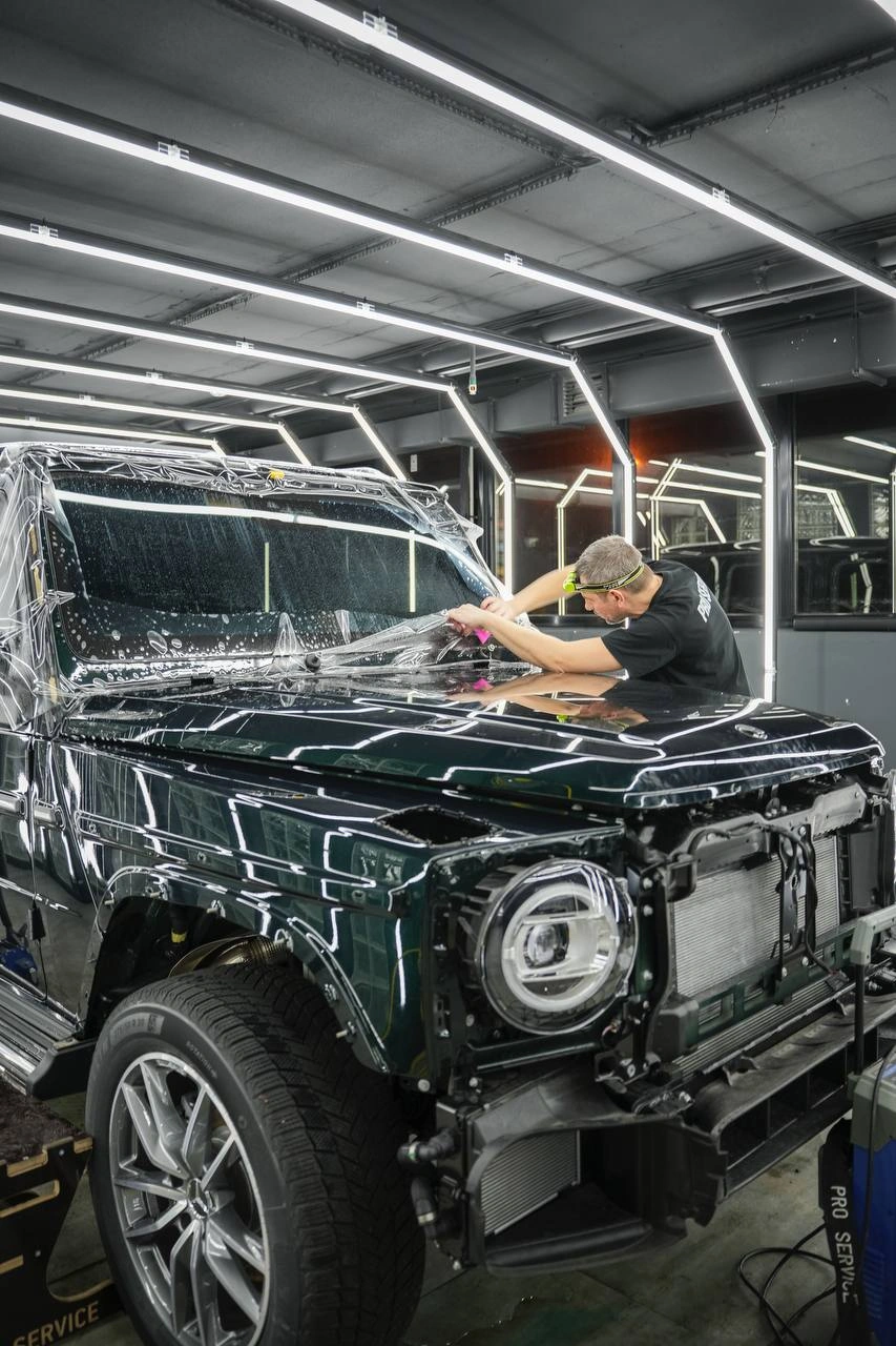 Mercedes-Benz G-Class — мастер работает у капота автомобиля со снятым передним бампером