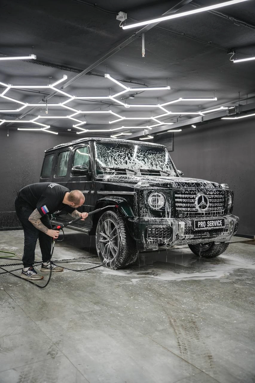 Mercedes-Benz G-Class — мастер очищает переднее колесо внедорожника, кузов покрыт пеной