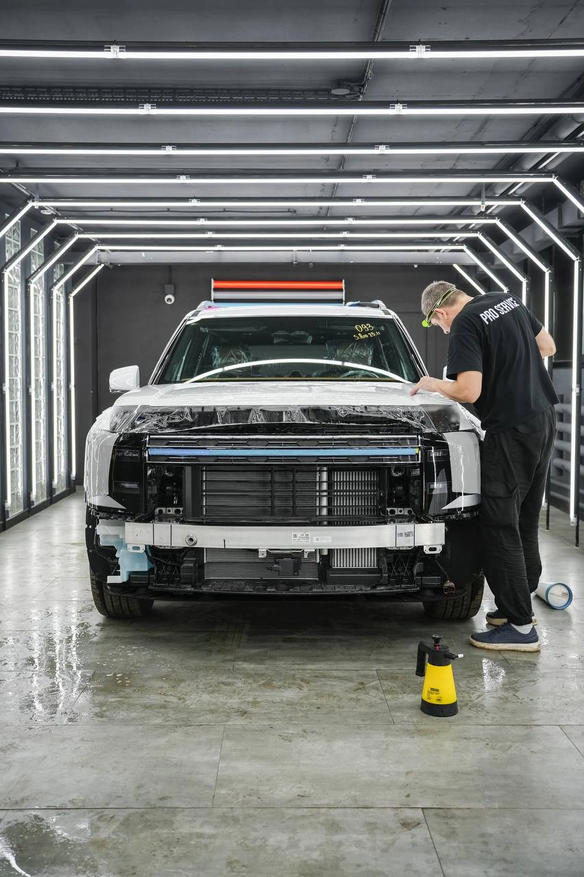 Мастер оклеивает переднюю часть Hyundai Palisade при разобранном бампере.