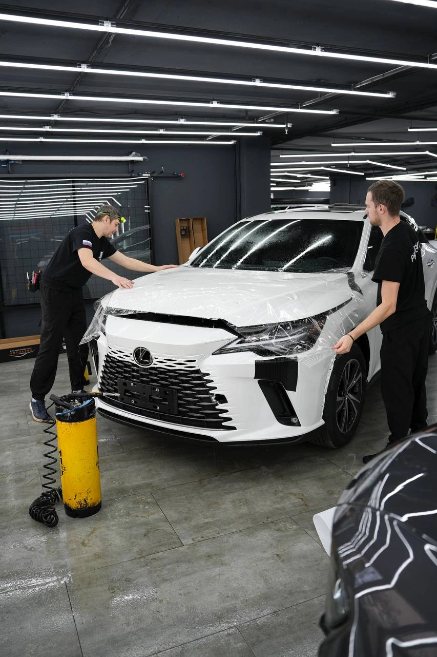 Lexus RX — мастера растягивают плёнку над капотом белого кроссовера
