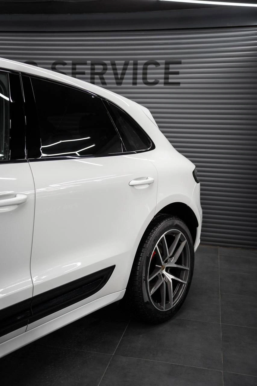 Боковая часть белого Porsche Macan: двери, заднее окно и заднее колесо крупным планом.