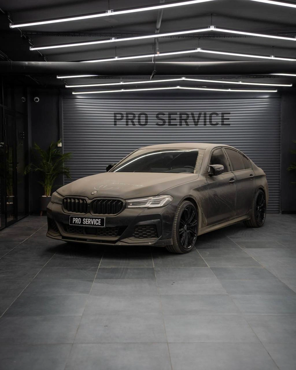 BMW 5 G30 в студии: капот и передние кузовные панели покрыты заметным слоем пыли, вид спереди и сбоку.