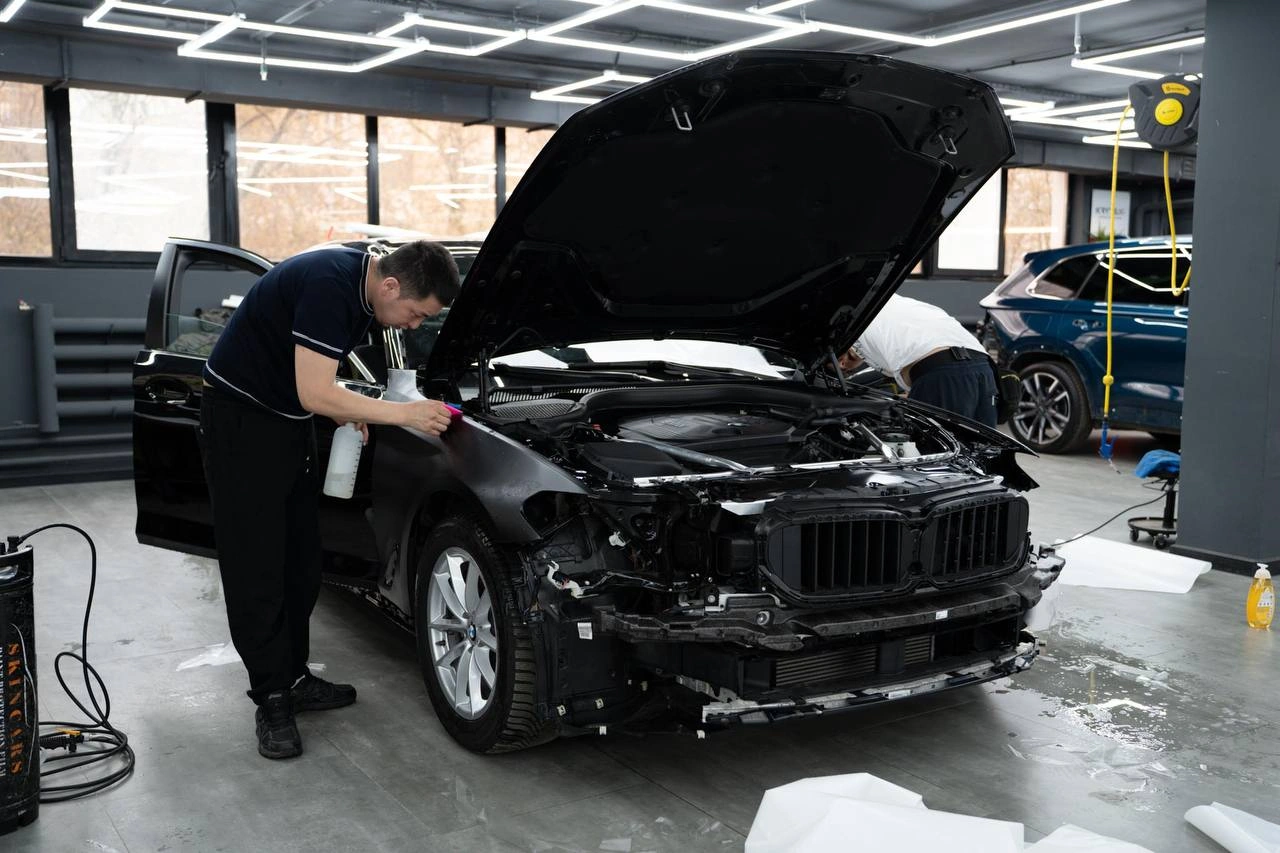 Очистка передней части BMW 5 после демонтажа бампера, с открытым капотом.
