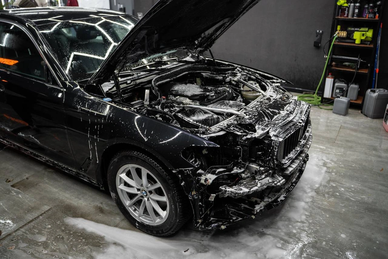 Мойка передней части BMW 5 перед оклейкой; капот открыт, кузов покрыт пеной.