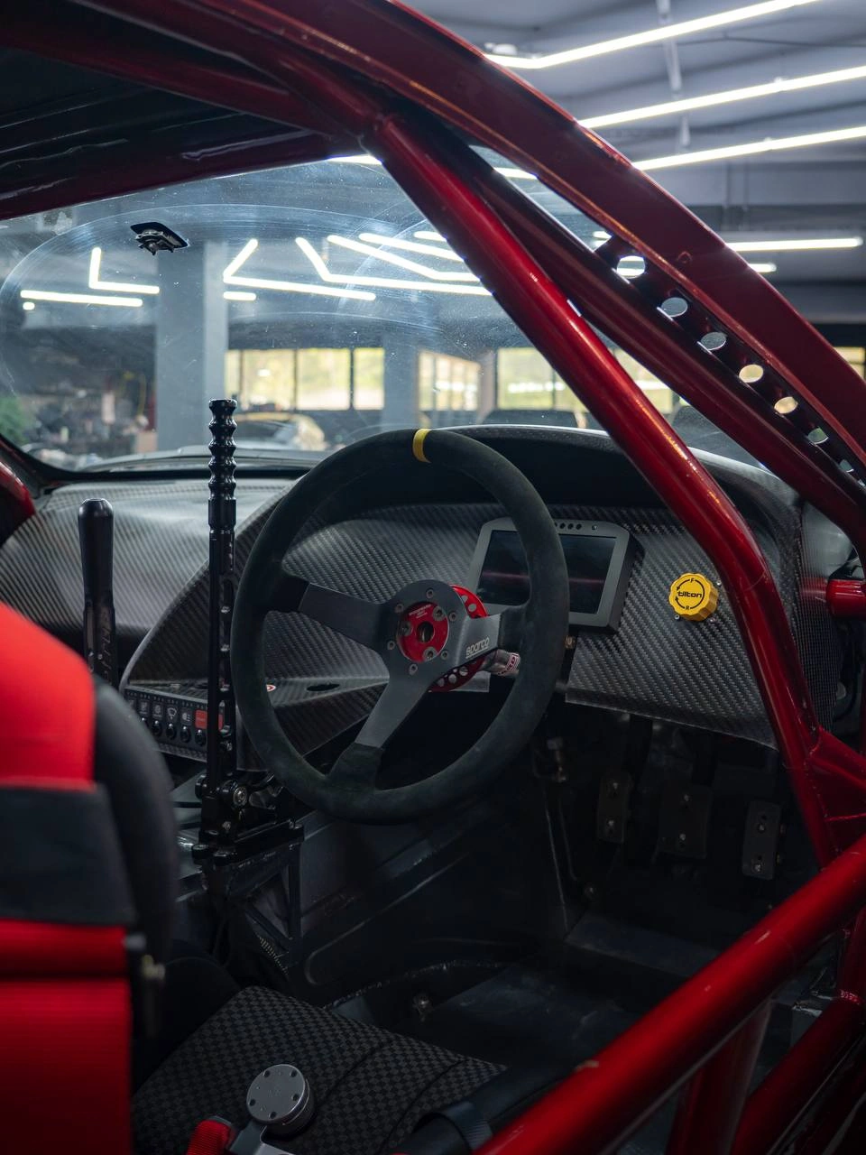 Салон Toyota Supra с красным каркасом, спортивным рулём и ковшеобразным сиденьем.