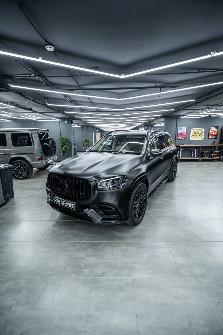 Mercedes-Benz GLS — чёрный внедорожник спереди под углом под линейным освещением студии