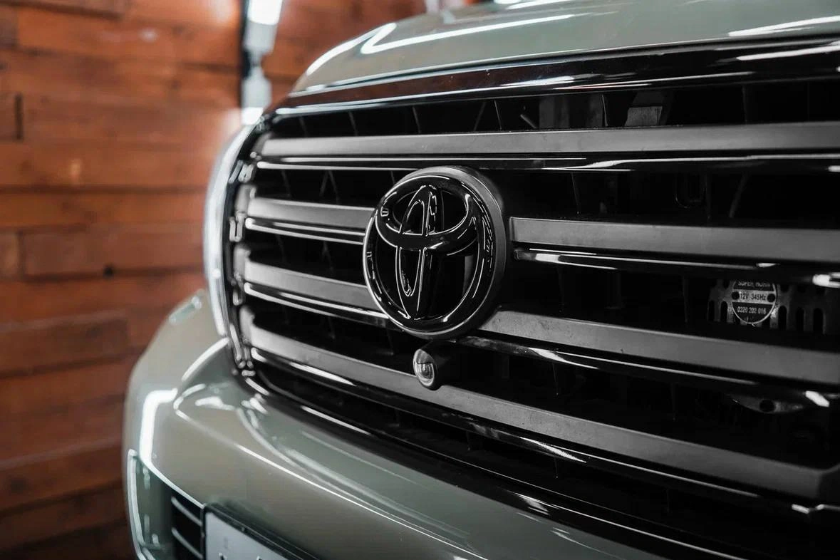Toyota Land Cruiser 200 — эмблема Toyota и горизонтальные планки решётки радиатора крупным планом