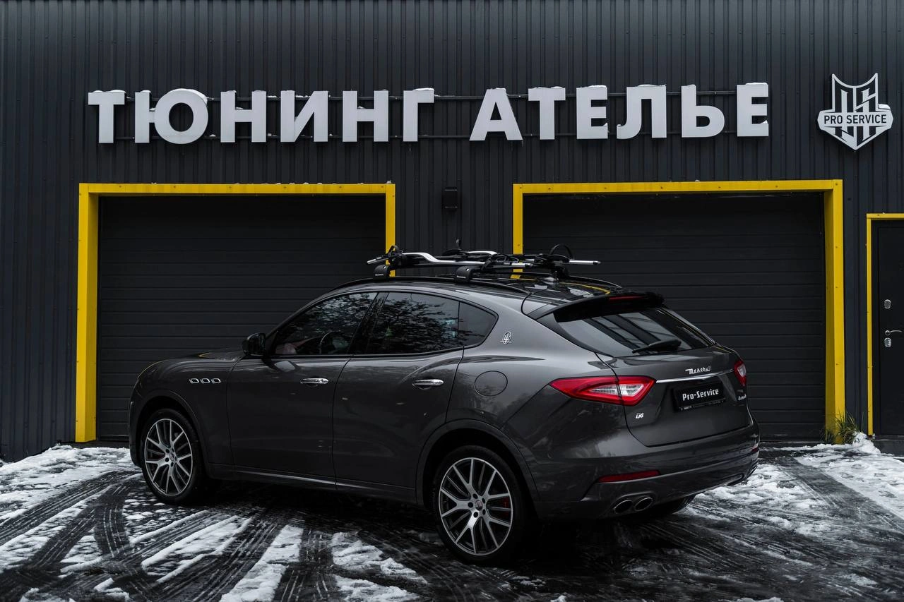 Maserati Levante — вид сзади под углом на заснеженной площадке, на крыше установлена багажная система